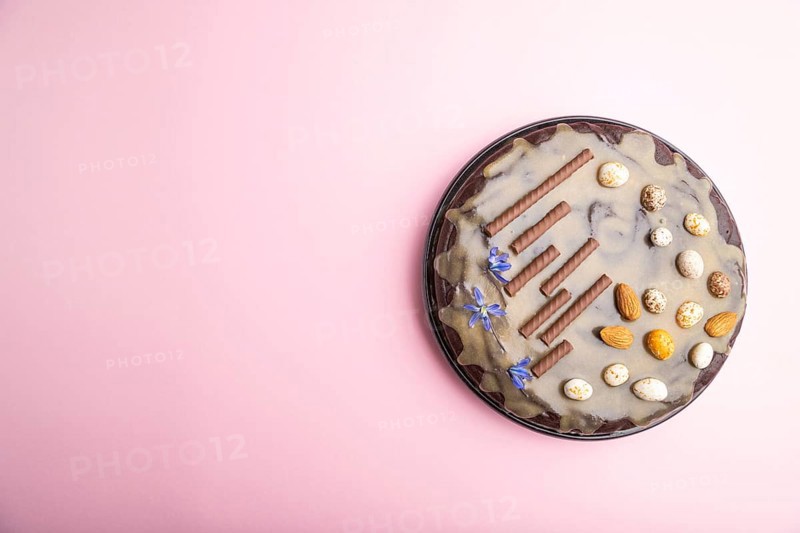 Homemade chocolate brownie cake with caramel cream and almonds on a pastel pink background. Top view, copy space, flat lay