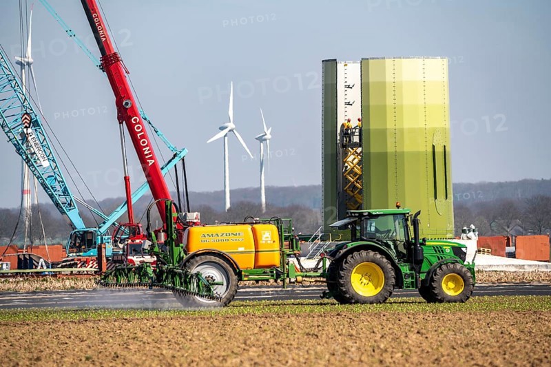 Construction of a wind turbine, Enercon steel pillar, near Kerken, Kleve district, on the Lower Rhine, farmer applying pesticide, North Rhine-Westphalia, Germany, Europe