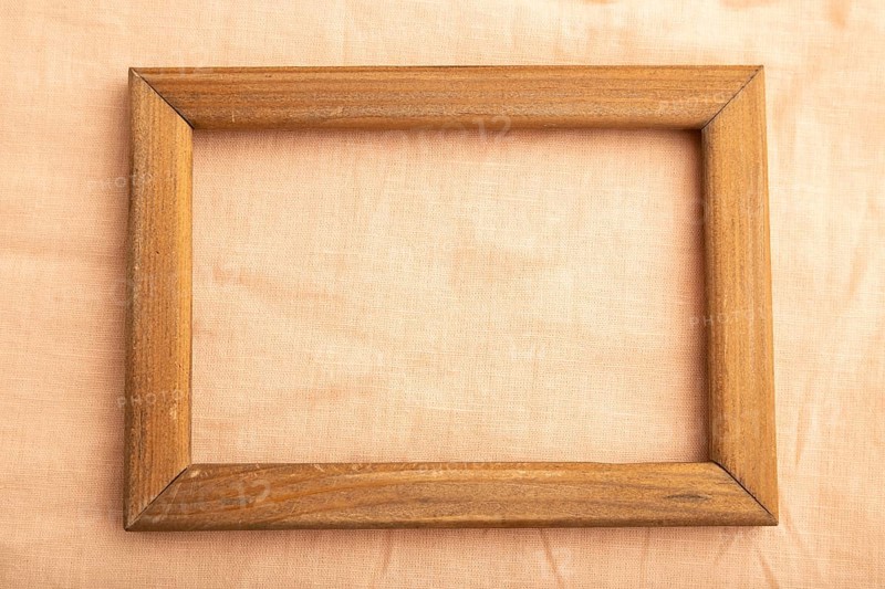 Wooden frame on smooth orange linen tissue. Top view, flat lay, natural textile background and texture