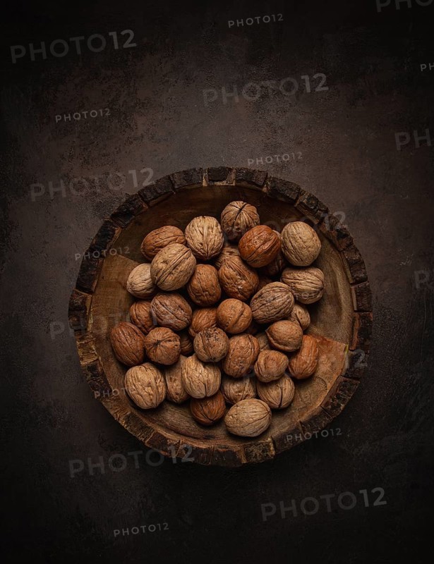 Fresh walnut in a shell, wooden plate, top view, no people