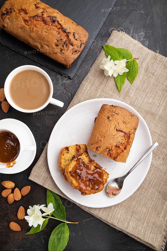 Homemade cake with raisins, almonds, soft caramel and a cup of coffee on a black concrete background and linen textile. top view, flat lay, close up