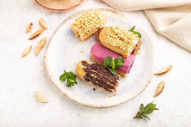 Set of eclair, traditional french dessert and cup of coffee on gray concrete background and linen textile. side view, close up, selective focus, still life. Breakfast, morning, concept