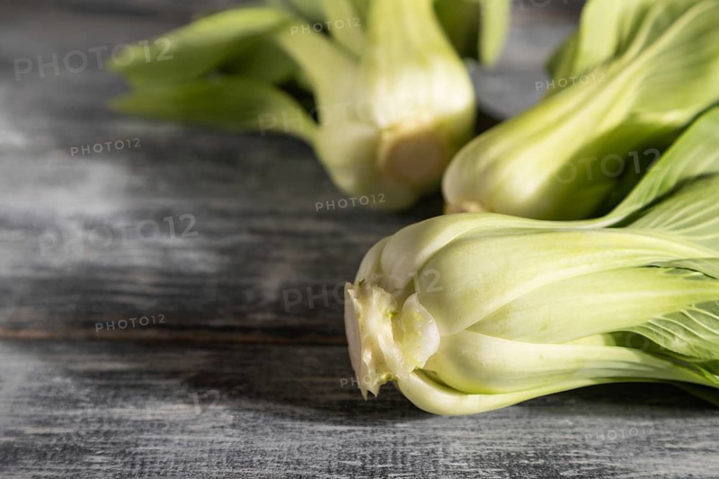 Fresh green bok choy or pac choi chinese cabbage on a gray wooden background. Hard light, contrast. Side view, copy space, selective focus