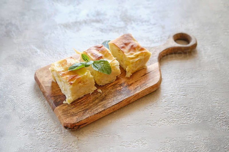 Overhead view of three pieces of Georgian cheese pie Achma on wooden cutting board