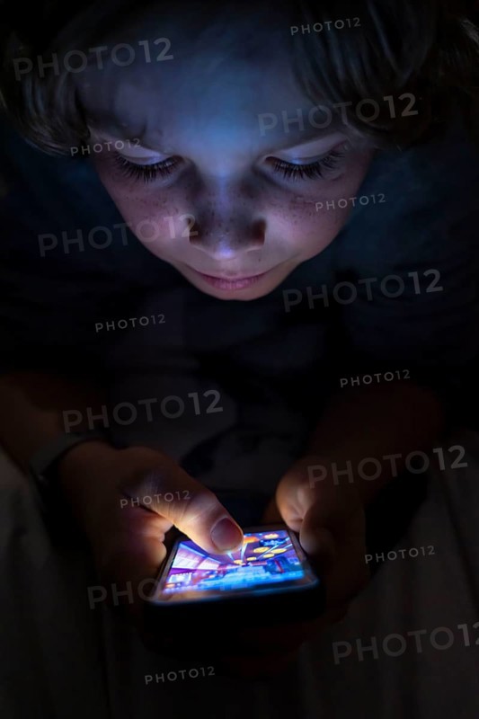A boy plays computer games on a mobile phone, smartphone