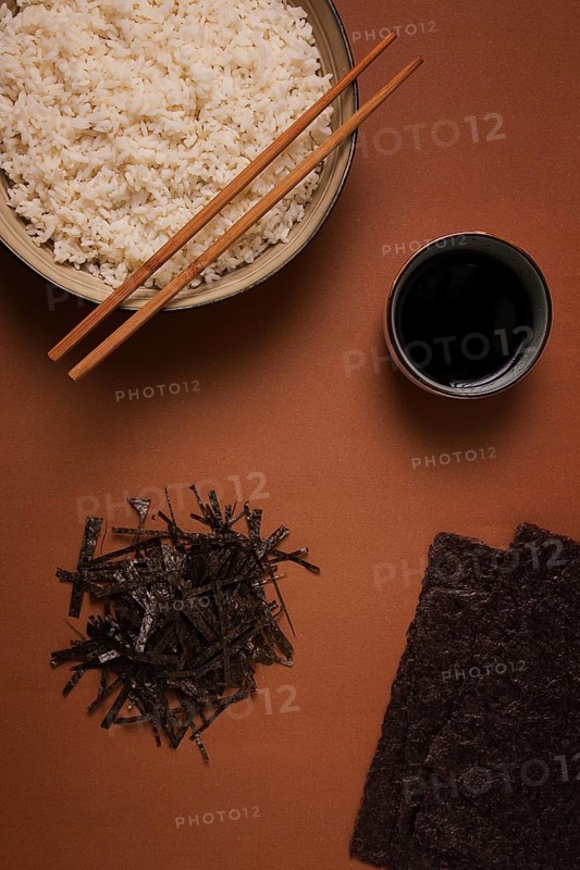 Leaves and chopped Nori shavings, with a cup of boiled rice, top view, on a brown background, selective focus, no people, concept