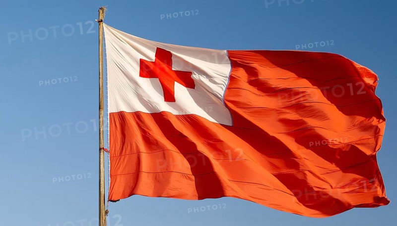 The flag of Tonga, Pacific island state, flutters in the wind, isolated against a blue sky