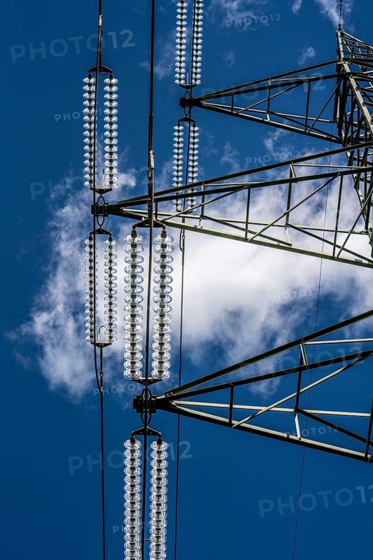 Insulators made of glass on a high-voltage line, they hang on the pylons as a suspension device between the pylon and the live, non-insulated cable, extra-high voltage line, symbolic image energy