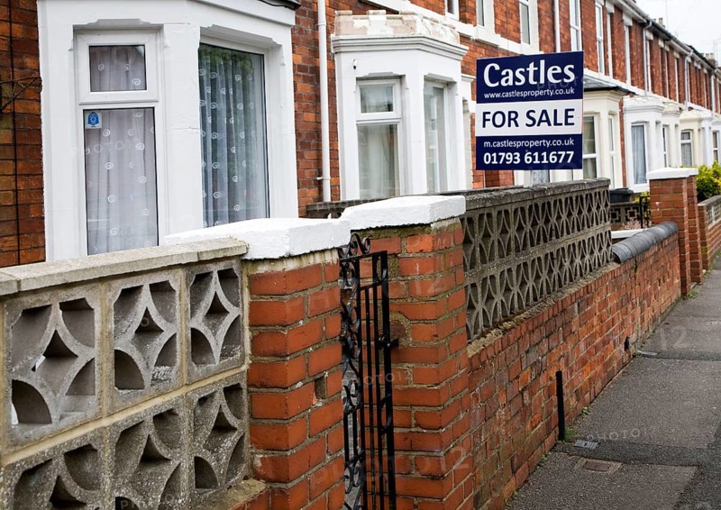 Estate agent for sale sign outside red brick terraced house in central Swindon, England, United Kingdom, Europe