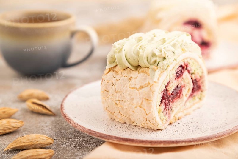 Roll biscuit cake with cream cheese and jam, cup of coffee on brown concrete background and orange linen textile. side view, close up, selective focus
