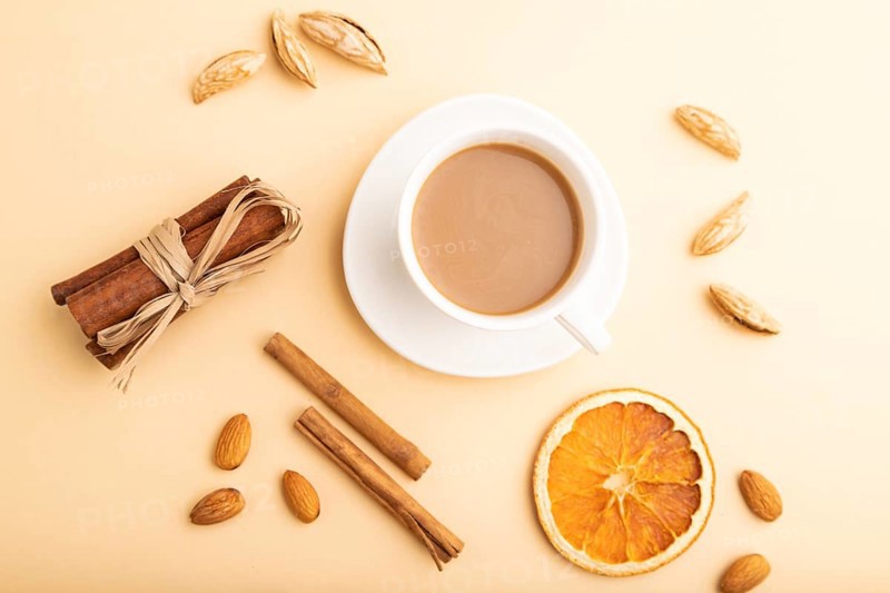 Composition with almonds, cinnamon and cup of coffee on orange pastel background. Blank, flat lay, top view, still life, close up