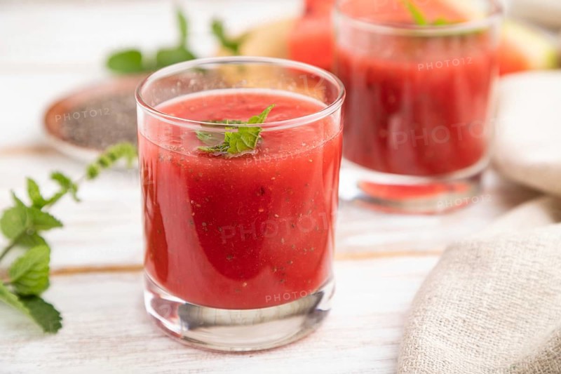 Watermelon juice with chia seeds and mint in glass on a white wooden background with linen textile. Healthy drink concept. Side view, close up, selective focus