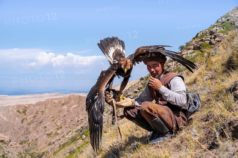 Traditional Kyrgyz eagle hunter with eagle in the mountains, near Kysyl-Suu, Kyrgyzstan, Asia