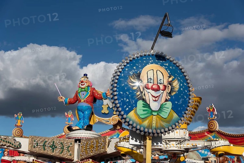 Colourfully decorated carousel with clown figure and blue sky in the background at a fairground, Magdeburg, Saxony-Anhalt, Germany, Europe