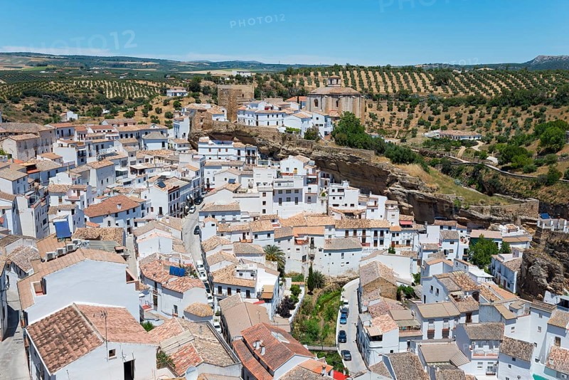 A white village with tiled roofs, embedded in a rock formation, surrounded by rural landscape, cave dwellings, Setenil de las Bodegas, Cadiz, Andalusia, Spain, Europe