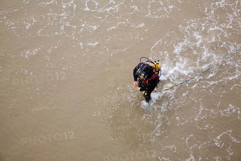 Looking down from above at professional diver on a beach about to enter the sea to work on the pier at Cromer, north Norfolk coast, England, United Kingdom, Europe