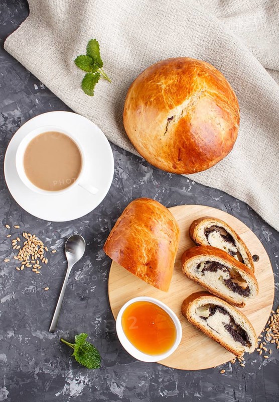 Homemade yeast buns and rolls with poppy seeds and honey on a black concrete background with a cup of coffee. top view, flat lay