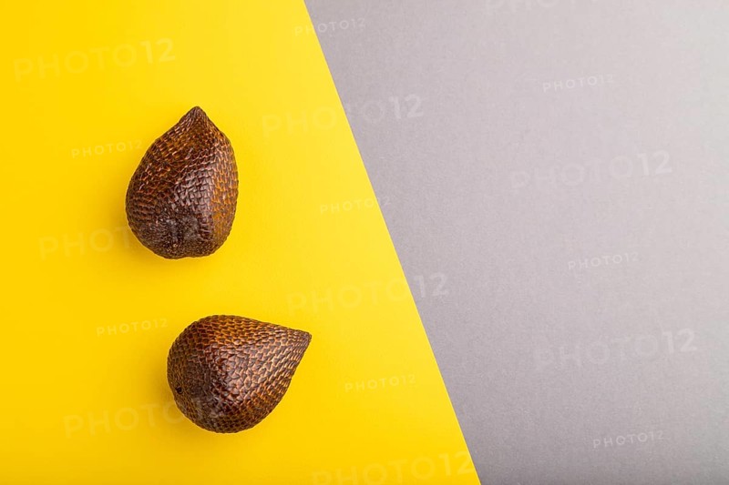 Salak or snake fruit on gray and yellow pastel background. Top view, flat lay, copy space. Tropical, healthy food, summer, exotic, minimalism