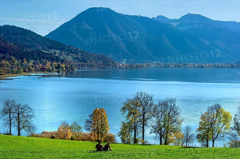 Tegernsee with Wallberg, couple sitting on a green meadow and looking at the lake, trees silhouetted on the shore, Mangfall mountains, Bavarian Alps, Alps, Upper Bavaria, Bavaria, Germany, Europe