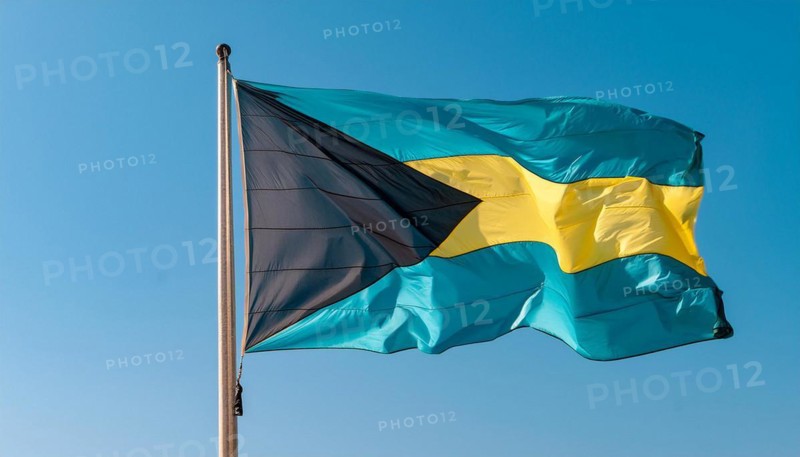The flag of the Bahamas flutters in the wind, isolated against a blue sky