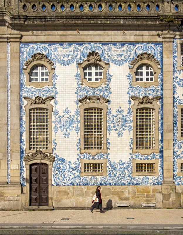 Woman passes by the facade of Igreja do Carmo church, adorned with intricate blue and white tiles, Porto, Portugal, Europe