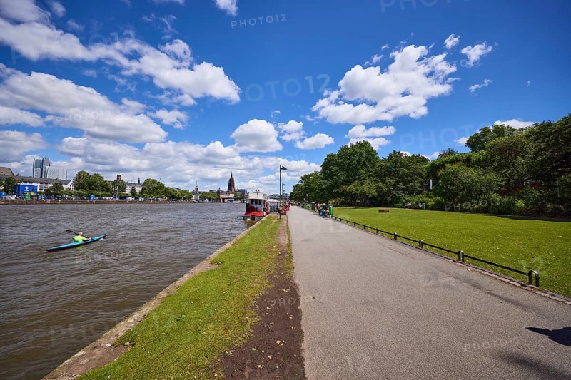Riverside promenade and Main with canoeists under a blue sky with cumulus clouds in Frankfurt am Main, Hesse, Germany, Europe