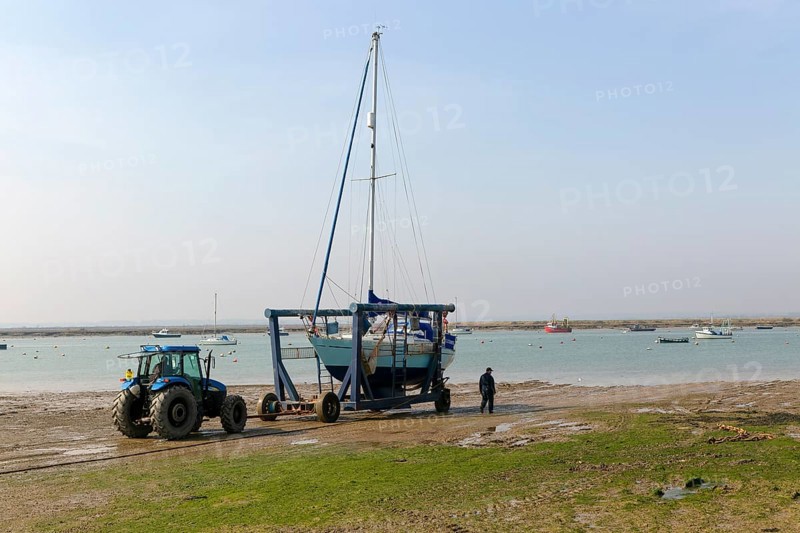 Tractor launching boat in cradle, River Blackwater estuary, West Mersea, Mersea Island, Essex, England, UK