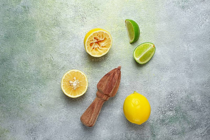 Wooden citrus reamer, manual lemon juicer, made of acacia wood, with citrus fruits on the table, top view