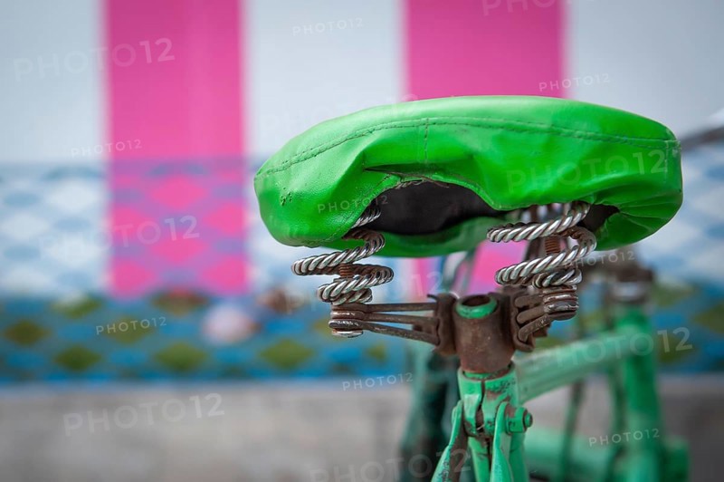 Green bicycle saddle, green bicycle in front of white-pink coloured temple outer wall, Tamil Nadu, India, Asia