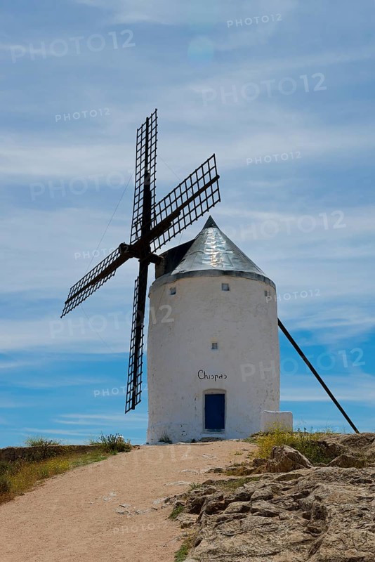An old windmill under a blue sky with clouds at the end of a dirt road in a rural landscape, Consuegra, Toledo, Castilla-La Mancha, Route of Don Quixote, Spain, Europe