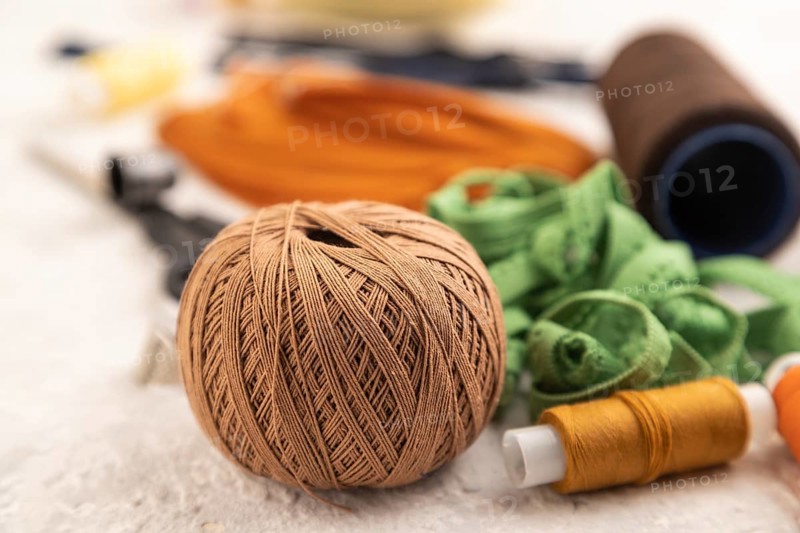 Sewing accessories: scissors, thread, thimbles, braid on gray concrete background. Side view, close up, selective focus