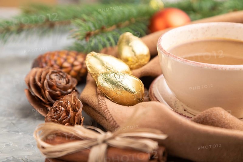 Christmas or New Year composition. Decorations, cones, cinnamon, fir and spruce branches, cup of coffee, wool scarf on a gray concrete background. Side view, close up, selective focus