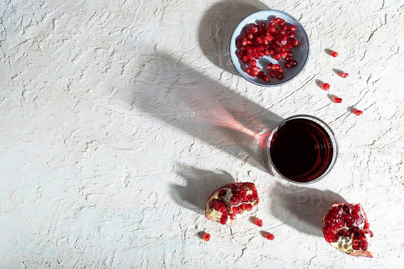 Glass of pomegranate juice on a white concrete background. Hard light, contrast. Top view, copy space, flat lay