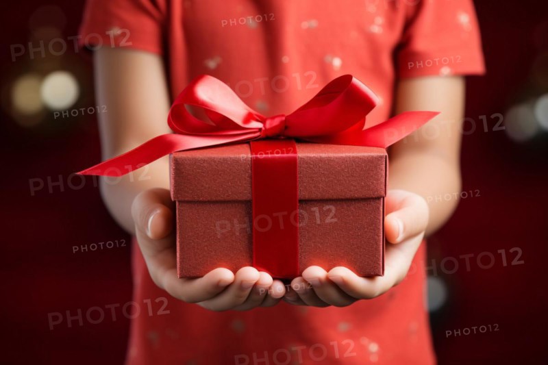 Child's hands holding red Mothers's day or birthday gift box. KI generiert, generiert, AI generated