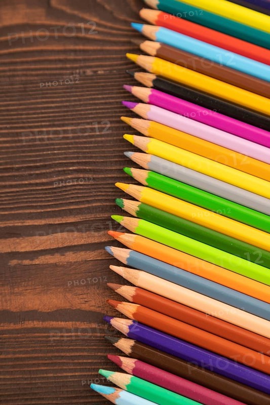 Set of watercolor pencils on brown wooden background. Top view, flat lay, close up