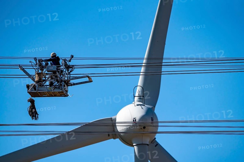 Construction of a new line route, 380 KV extra-high voltage line between Osterath and Gohr, near Neuss, fitters in cable trolleys, on the conductor cables, installing field spacers at great heights, wind power station, North Rhine-Westphalia, Germany, Europe