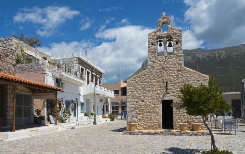 Village square with traditional stone church and white buildings under a cloudy blue sky, Church of St Athanasios, Areopoli, Areopolis, Tsimova, Itylo, Anatoliki Mani, Mani, Laconia, Peloponnese, Greece, Europe