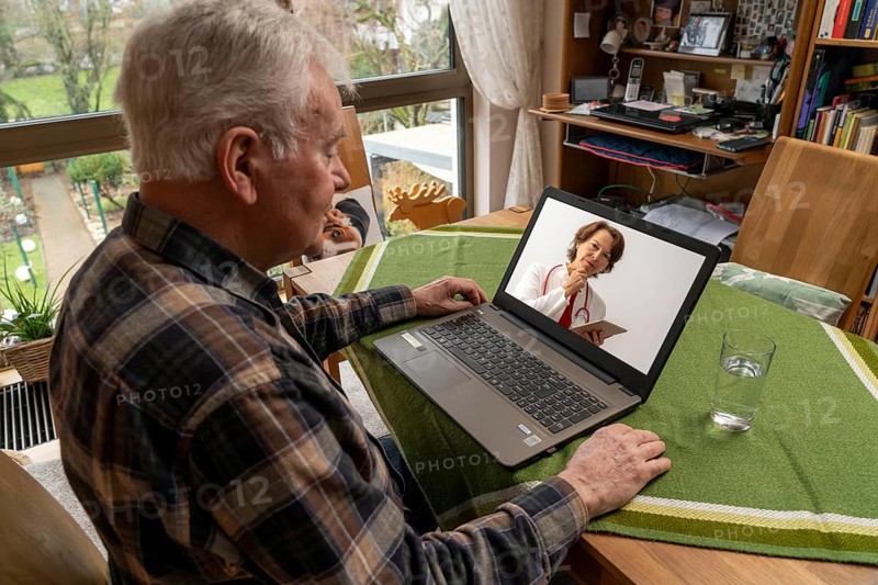 Symbolic image of telemedicine, elderly patient speaking to a doctor in a video conference from home