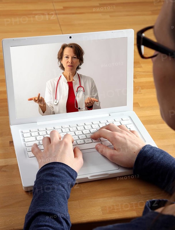 Symbolic image of telemedicine, patient speaking to a doctor in a video conference from home