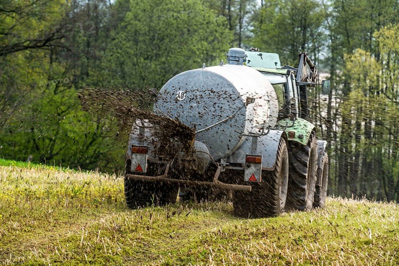 Slurry is spread on a field with a tractor from a slurry tanker to fertilise the farmland, North Rhine-Westphalia, Germany, Europe