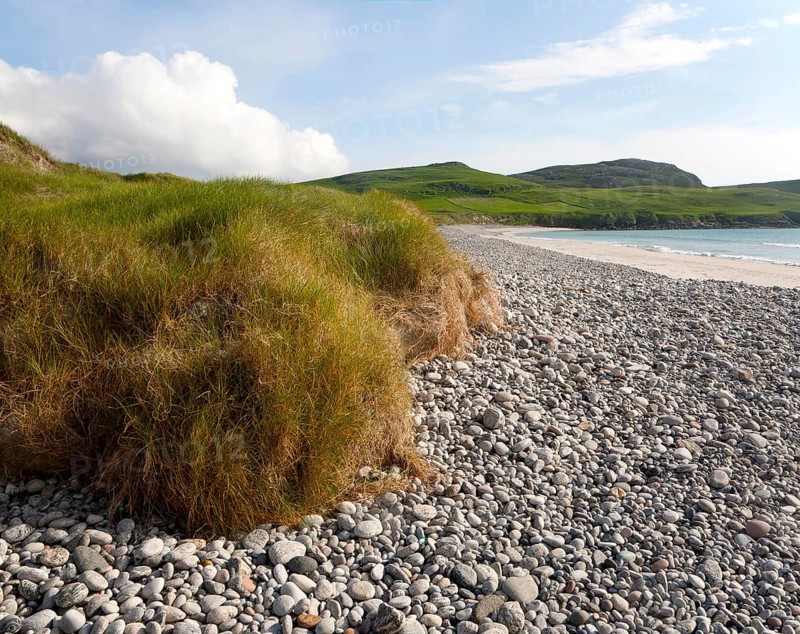 Low angle view of pebbles, sandy beach and dune vegetation on Traigh Siar beach, Vatersay, Barra, Outer Hebrides, Scotland, UK