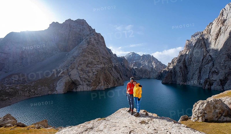 Couple at the blue mountain lake between rocky steep mountain peaks, Kol Suu Lake, Sary Beles Mountains, Naryn Province, Kyrgyzstan, Asia