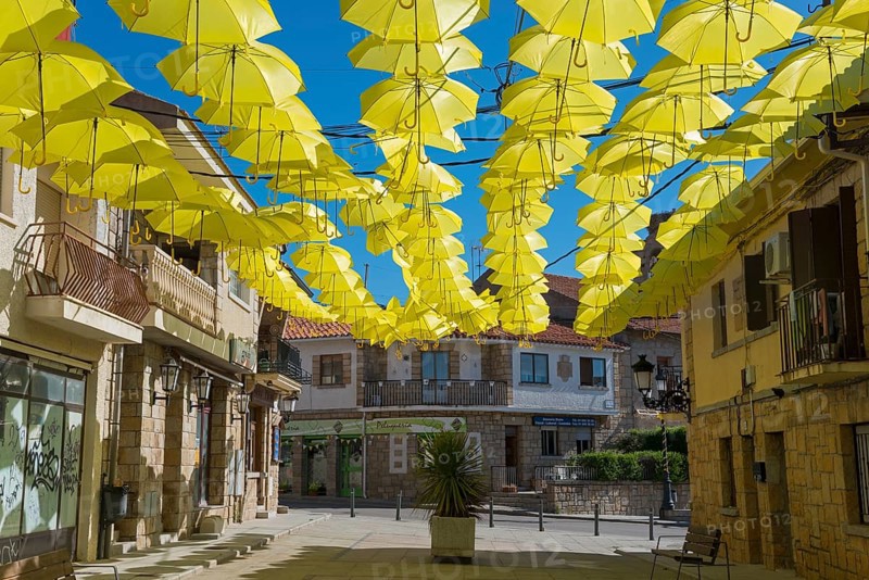 Street full of yellow umbrellas forming an artistic shadow installation under a blue sky and old buildings, Old Town, Los Molinos, Cuenca del Guadarrama, Madrid, Spain, Europe
