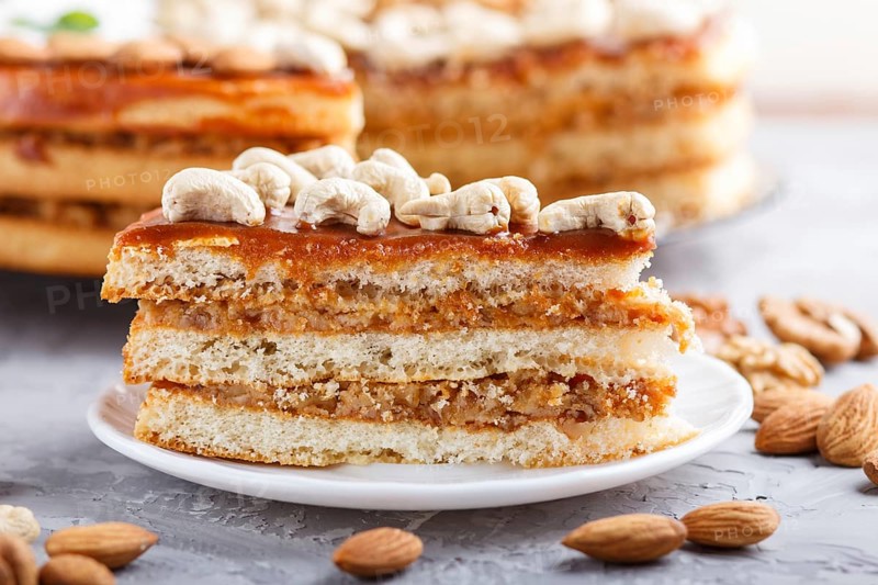 Piece of homemade cake with caramel cream and nuts on a gray concrete background. side view, close up, selective focus