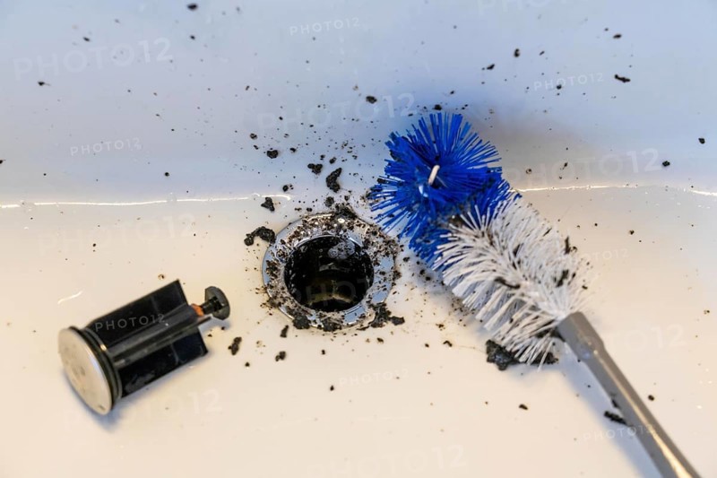 Cleaning a sink, hand basin, bathroom, with the help of a longer brush, the dirt, deposits, mould accumulated over time are removed, housework, cleaning work