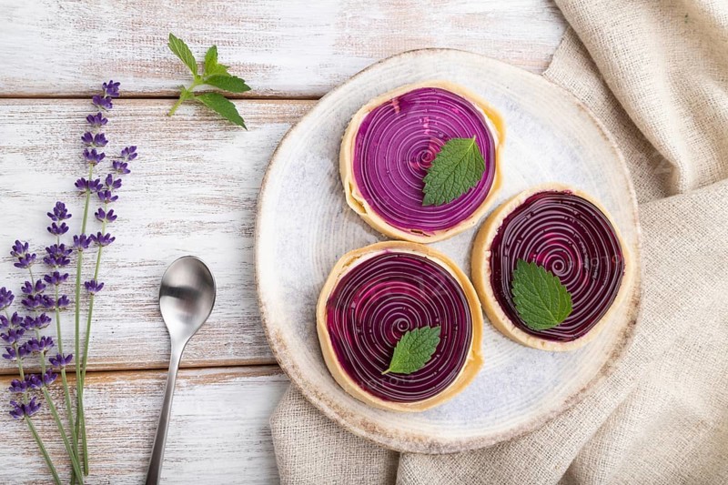 Sweet tartlets with jelly and milk cream with cup of coffee on a white wooden background and linen textile. top view, flat lay, close up