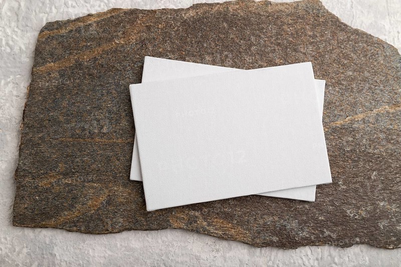 White paper business card, mockup with natural stone on gray concrete background. Blank, flat lay, top view, still life, copy space, canvas