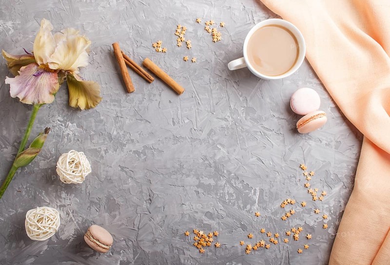 Multicolored iris flowers and a cup of coffee on a gray concrete background. Morninig, spring, fashion composition. Flat lay, top view, copy space