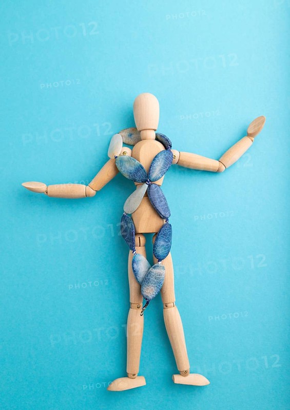 Wooden mannequin with blue agate beads on blue pastel background. copy space, isolated, luxury, bad taste, raunch, concept