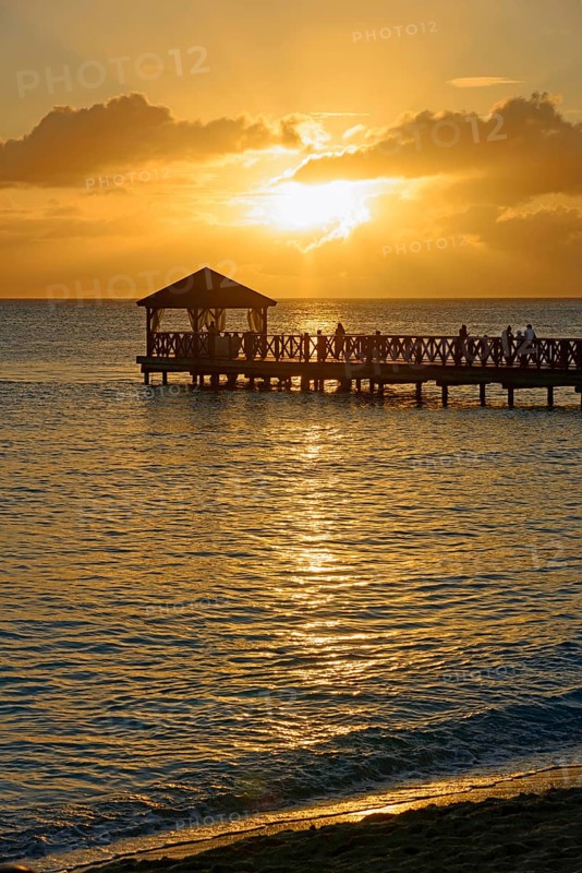 People on a jetty watching the sunset over the sea with beautiful reflection on the water, Dominicus beach, Bayahibe, Dominican Republic, Hispaniola, Caribbean, America, Central America